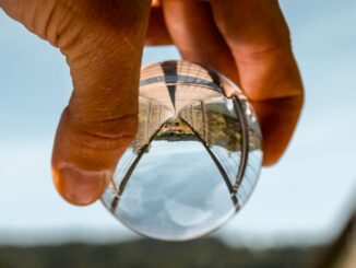 A hand is holding a glass ball and image of a bridge shown inside is flipped